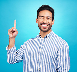 Image showing Point, excited and portrait of Asian man on blue background for news, information and announcement. Advertising, studio mockup and happy male pointing for copy space, promotion and showing gesture