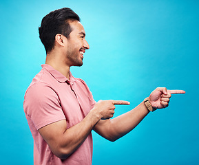 Image showing Mockup, happy and man point on blue background for news, information and deal announcement. Advertising, branding and excited male pointing for copy space, promotion and showing gesture in studio