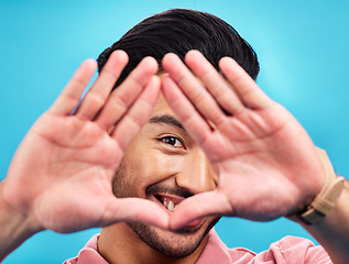 Image showing Frame, hands and portrait of Asian man on blue background with smile, confidence and happiness. Perspective, framing and face of happy male in studio for photography, profile picture and vision sign