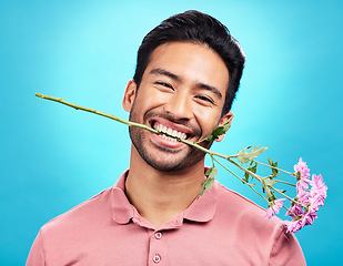 Image showing Teeth, flower and happy with portrait of man in studio for celebration, gift and romance. Funny, goofy and present with male isolated on blue background for happiness, smile and valentines day mockup