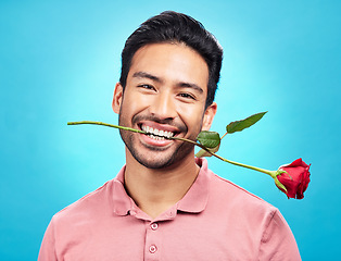 Image showing Teeth, flower and rose with portrait of man in studio for celebration, gift and romance. Funny, goofy and present with male isolated on blue background for happiness, smile and valentines day mockup