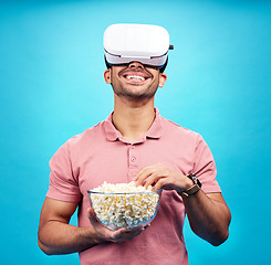 Image showing Vr, popcorn and movie with man in studio for streaming, met verse and cinema. Happy, technology and digital with male watching tv on blue background for virtual reality, television and future theater