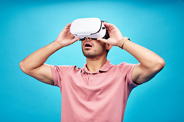 Image showing Man, virtual reality and surprise with UX and metaverse, futuristic technology isolated on blue background. Gamer, VR headset or goggles, male person in digital world with wow expression in studio