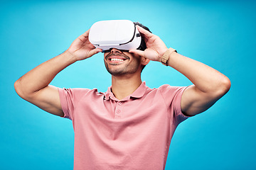 Image showing Man with smile, virtual reality and metaverse with futuristic tech, UX and simulation isolated on blue background. Future technology, digital world and gaming male in VR goggles streaming in studio