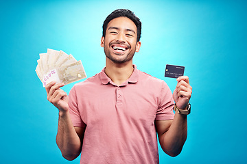 Image showing Money, portrait and credit card by happy man in studio with savings, finance or investment growth on blue background. Cash, face and asian guy smile for banking, success or financial freedom isolated