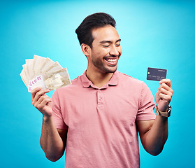 Image showing Smile, money and credit card by happy man in studio with savings, finance or investment growth on blue background. Cash, joy and asian guy excited for banking, success or financial freedom isolated