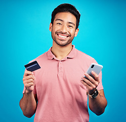 Image showing Man with smartphone, credit card and happy in portrait, ecommerce and fintech isolated on blue background. Online shopping, internet banking and finance, technology and male with bank app in studio