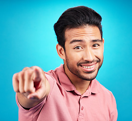 Image showing Pointing, you and portrait of man. in studio for motivation, choice and decision. Happy, smile and yes with male and hand gesture isolated on blue background for option, offer and emoji mockup