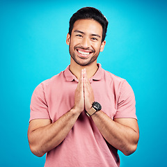 Image showing Happy, prayer hands and portrait of a man in a studio with a peaceful, positive and good mindset. Happiness, smile and face of a male model with a grateful hand gesture isolated by a blue background.