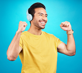 Image showing Happy, music and headphones with man in studio for streaming, podcast and dance. Smile, mobile radio and technology with male isolated on blue background for listening, audio and freedom mockup