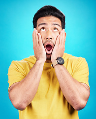 Image showing Man, wow and shocked at surprise or announcement in studio with hands on face and mouth open. Male model person on a blue background while thinking of gossip, sale or promotion with comic emoji