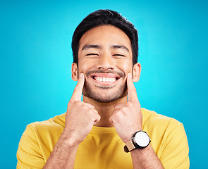 Image showing Teeth, smile and pointing with a man on a blue background in studio for dental care or oral hygiene. Portrait, face and happy with a handsome young male at the dentist for tooth care or whitening