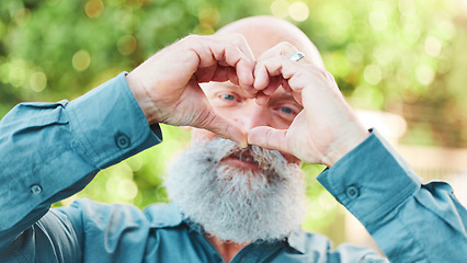 Image showing Portrait, hands and heart with a senior man outdoor in a garden during summer for love or health. Face, emoji and shape with a hand gesture by a mature male outside in a park for wellness or romance