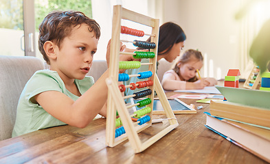 Image showing Education, maths and a boy counting on an abacus while learning in the living room of his home. Children, homework and study with a male school kid in his house for growth or child development