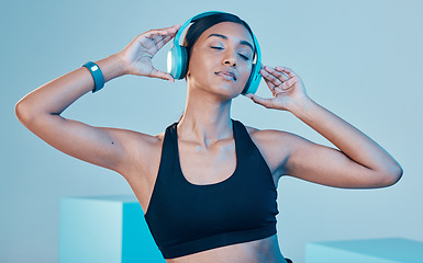 Image showing Headphones, fitness and woman isolated on blue background for workout, training or exercise music. Gen z, sports and biracial person listening on audio technology, mental health or wellness in studio