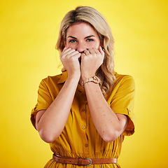 Image showing Portrait, shy and woman with fist on face in studio isolated on a yellow background. Female person, introvert and covering mouth with hands, peek and hiding, secret and embarrassed with gossip.