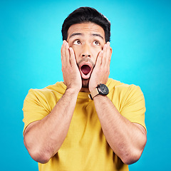 Image showing Wow, shocked and man with hands on face and mouth open for surprise or announcement in studio. Male model person on a blue background while thinking of gossip, sale or promotion with comic emoji