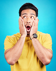 Image showing Wow, man and shocked at surprise in studio with announcement, hands on face and mouth open. Male model person on a blue background while scared or thinking of gossip, news or sale with comic emoji