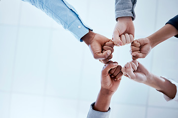 Image showing Business people, fist circle and teamwork in low angle, team building and trust in office. Solidarity, huddle and group or staff of men and women with hands together for unity, synergy or cooperation