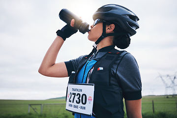 Image showing Fitness, cyclist or woman drinking water in park to hydrate, relax or healthy energy on exercise break. Tired thirsty girl athlete biker refreshing with liquid for hydration in training or workout