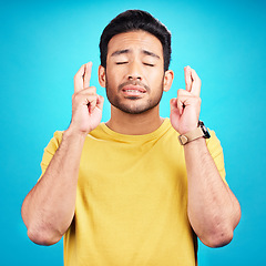 Image showing Hope, man and fingers crossed for luck in studio isolated on a blue background. Wish, hand gesture and male person with aspiration, hoping emoji and wait for good fortune, result or optimistic faith.