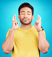 Image showing Hope, man and fingers crossed for miracle in studio isolated on a blue background. Wish, hand gesture or male person with aspiration, hopeful emoji and wait for good fortune, luck or optimistic faith