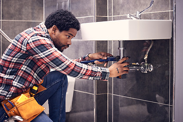 Image showing Black man, plumber and maintenance in bathroom, fixing sink pipe with wrench and plumbing industry. Manual labor, male with focus and trade, handyman doing repairs with tools on home renovation