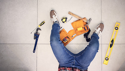 Image showing Above, man and tools for construction on the floor, home maintenance or plumbing check. Building, service and a plumber in a house for renovation upgrade, handyman services and contractor project