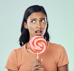 Image showing Thinking, lollipop and woman with candy in studio isolated on a green background. Idea, sweets and Indian person with snack, delicious sucker or sugar treats, dessert or confectionery junk food.