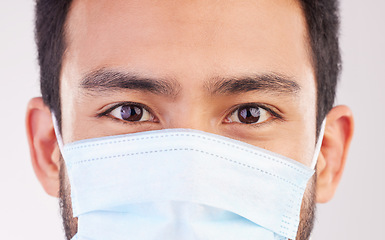 Image showing Doctor, portrait and man with mask for covid, compliance and safety in studio closeup. Facemask, prevention and eyes of male health expert at a clinic for help, treatment and healthcare control