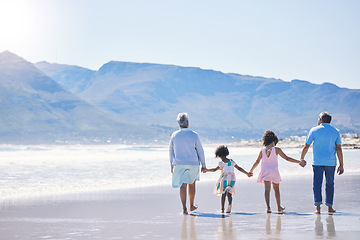 Image showing Walking, holding hands and grandparents at the beach with children for holiday and together by the sea. Back, summer and girl kids on a walk by the ocean with a senior man and woman for bonding