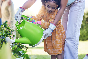 Image showing Children, watering plants and a mother teaching her daughter about growth or sustainability in the garden. Family, spring or gardening with a woman and female child outdoor in the backyard together