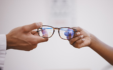 Image showing Glasses, optometry and hands of an optometrist and person for decision, buying and help with vision. Consulting, helping and an optician giving eyewear frames and prescription lenses to a customer