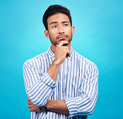 Image showing Thinking, planning and future with a man on a blue background in studio to consider a thought or option. Idea, mindset and contemplation with a handsome young person looking thoughtful about a choice