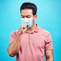 Image showing Covid cough, sick and a man with a cold isolated on a blue background in a studio. Healthcare, virus and an Asian person coughing with a face mask for flu, infection and disease during pandemic