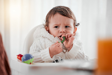 Image showing Baby, angry child and eating vegetables in home for health, wellness and nutrition. Upset kid, high chair and food, veggies or breakfast in kitchen for healthy diet, growth and development in house.