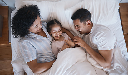 Image showing Mom, dad and child tickle in a bedroom bed in the morning at family home with bonding. Laughing, mother and father with a young girl being playful and happy with a smile and youth together with love