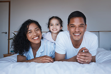 Image showing Bonding, love and portrait of a family in a bedroom in their relaxing, spending quality time and bonding together. Happy, smile and girl child laying on a bed with her parents in their modern home.