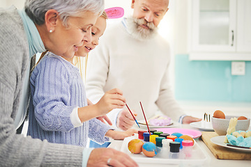 Image showing Easter, paint and a fun girl with her grandparents in their home for love, bonding or celebration together. Family, kitchen or egg with senior couple and grandchild in a house for creative painting