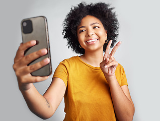 Image showing Peace sign, selfie and smile with woman in studio for social media, connection and profile picture. Happy, emoji and technology with female on white background for online update, trendy and gen z