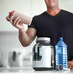 Image showing Man, hands and protein shake for nutrition, muscle gain or body mass product and supplement on kitchen table. Hand of male bodybuilder preparing pre workout drink for exercise or healthy meal at home