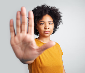 Image showing Portrait, palm and warning with a woman in studio on a gray background for control or to stop abuse. Hand, protest and body language with an attractive young female person saying no in disagreement