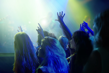 Image showing Crowd, neon lights and people at concert or music festival dancing with energy and hands up at night event. Dance, fun and group of excited fans in arena at rock band performance or audience at party