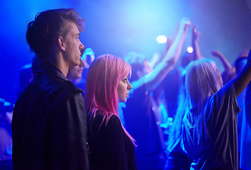 Image showing Couple in crowd, man and woman at music festival, neon lights and watching live band performance on stage. Dance, group of people at party and blue lighting, fans on date at rock concert together.