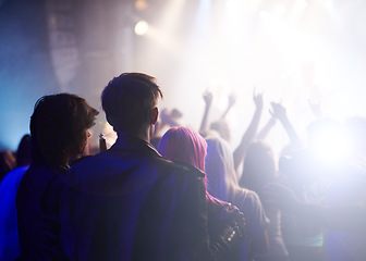 Image showing Dance, rock and friends in crowd at music festival from back, watching live band performance on stage. Audience in arena, lights and group of people at party, fans of musician at concert together.