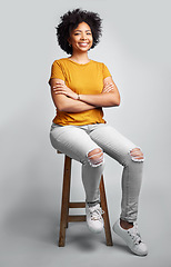 Image showing Portrait, smile and woman with arms crossed on stool in studio isolated on a gray background. Chair, confidence and happy African female person from South Africa with stylish fashion, gen z or trendy