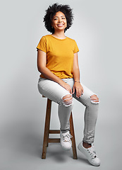 Image showing Portrait, smile and woman sitting on stool in studio isolated on a white background. Chair, confidence and happy African female person from South Africa with stylish fashion, gen z or trendy clothing