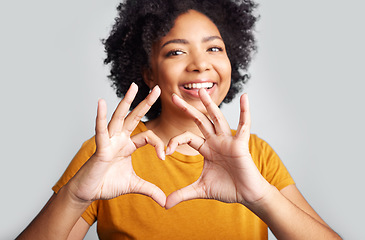 Image showing Portrait of happy woman, heart and hand in studio, white background and care of kindness, emoji and icon. Young female model, love and finger shape with hands for thank you, trust and hope with smile