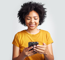 Image showing Happy, woman and cellphone texting on white background of notification, social media post and online chat. Young african female model typing on smartphone, mobile app or download technology in studio