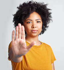 Image showing Woman, stop and hand in studio portrait for human rights abuse, racism and afro by gray background. Girl model, gesture or activism for discrimination, justice or protest for freedom, peace or vote